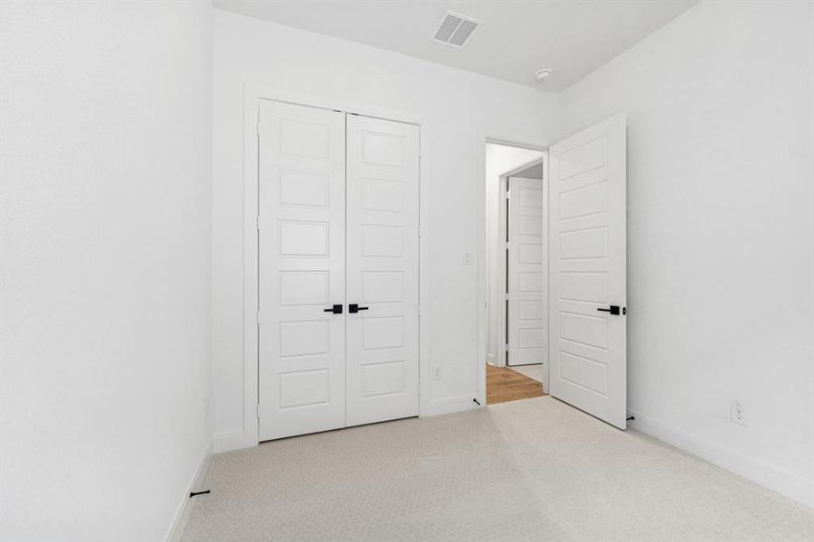 Unfurnished bedroom with light carpet and a closet Unfurnished bedroom with light carpet and a closet