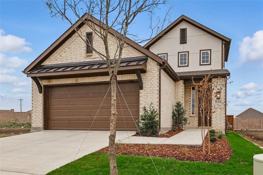 View of front of property with driveway, brick siding, a standing seam roof, an attached garage, and a metal roof