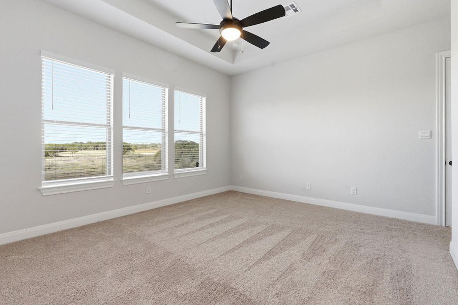 Spare room with a tray ceiling, ceiling fan, and light carpet
