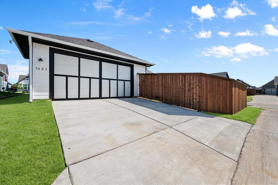 Rear view of property featuring alley access to the two car garage, garage door side lighting and 2 extra parking places.