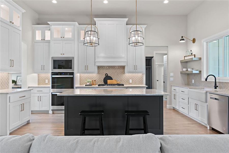 Kitchen featuring pendant lighting, white cabinetry, stainless steel appliances, and light hardwood / wood-style floors