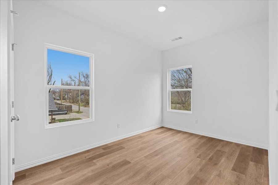 Bright secondary bedroom featuring wood-look flooring, neutral paint, and ample natural light. Comfortable layout with clean, modern finishes.