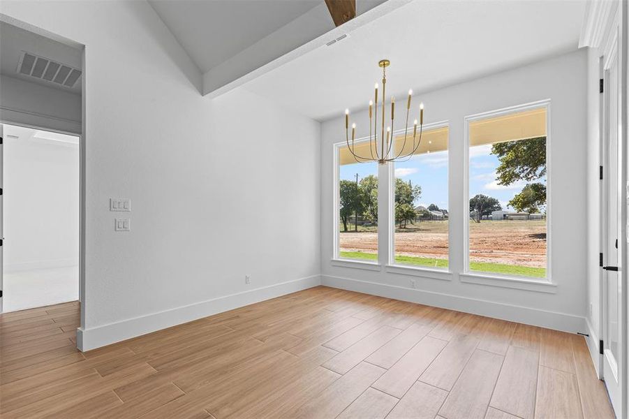 Unfurnished dining area with a chandelier, light wood-style floors, and beamed ceiling