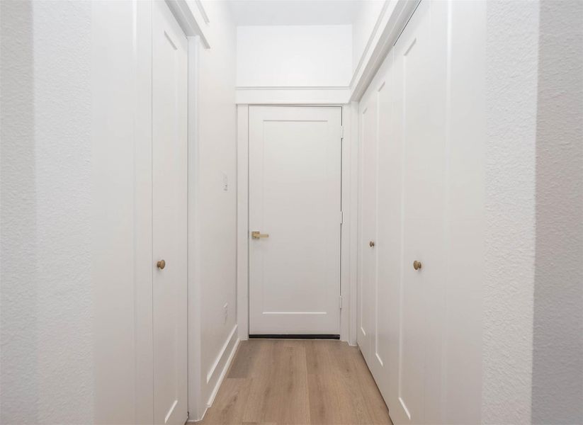 Hallway leading to the garage with pantry on the left and utility room on the right.