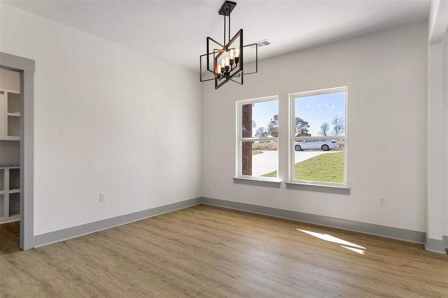 Unfurnished dining area featuring hanging lights and light wood-type flooring