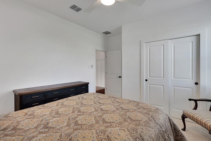 This 3rd bedroom features a cozy atmosphere with neutral walls, a ceiling fan, and ample storage space