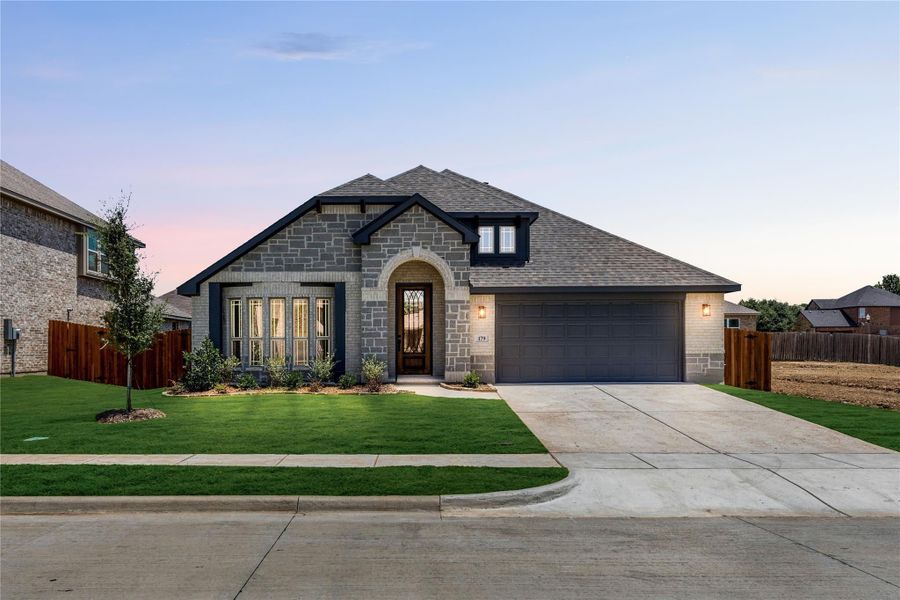 Single-story home with stone and brick exterior, arched entry, two-car garage, and manicured front lawn Single-story home with stone and brick exterior, arched entry, two-car garage, and manicured front lawn