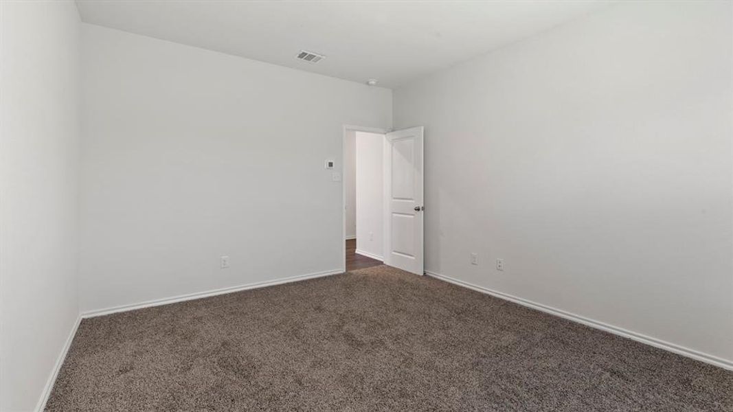 Spacious room featuring neutral carpeting, white wall paint, and crisp white baseboards