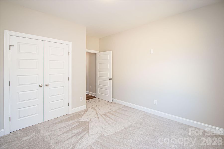 This second bedroom boasts plush carpeting, a roomy closet, a large window for natural light, and a pre-installed outlet for a ceiling fan.