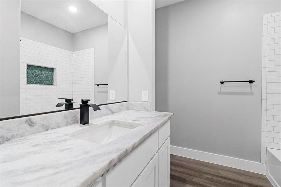 Bathroom featuring wood-type flooring, tiled shower / bath, and vanity