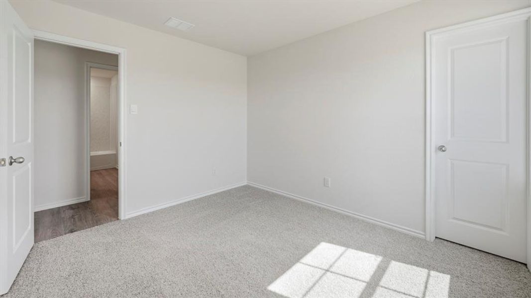 Unfurnished bedroom with light carpet and baseboards