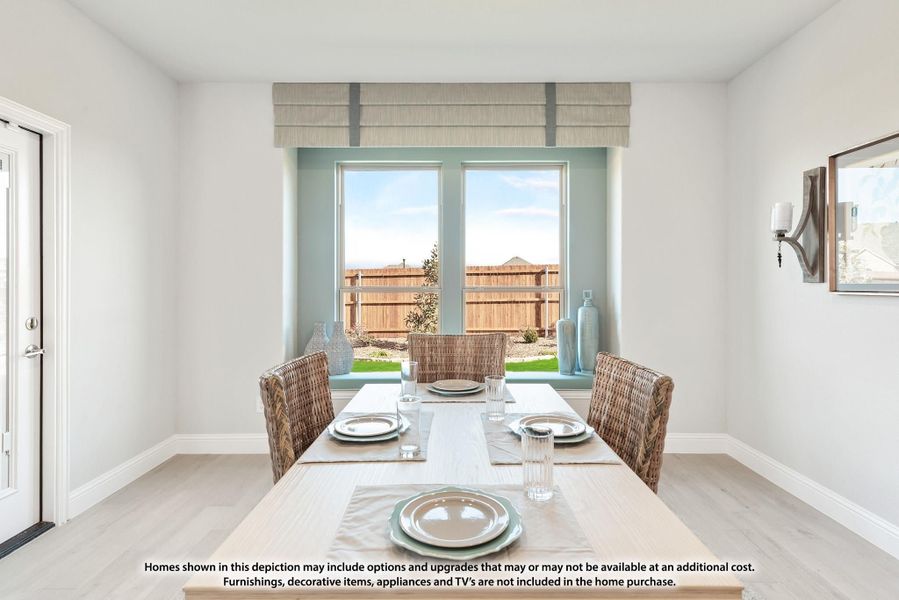Dining room with wood table, wicker chairs, and two windows overlooking a backyard fence