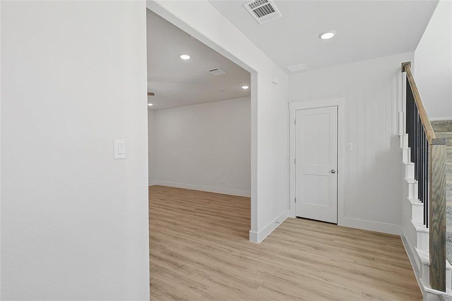 Entryway featuring light wood-style flooring, a white paneled door, recessed lighting, and a staircase with a wooden handrail and black balusters
