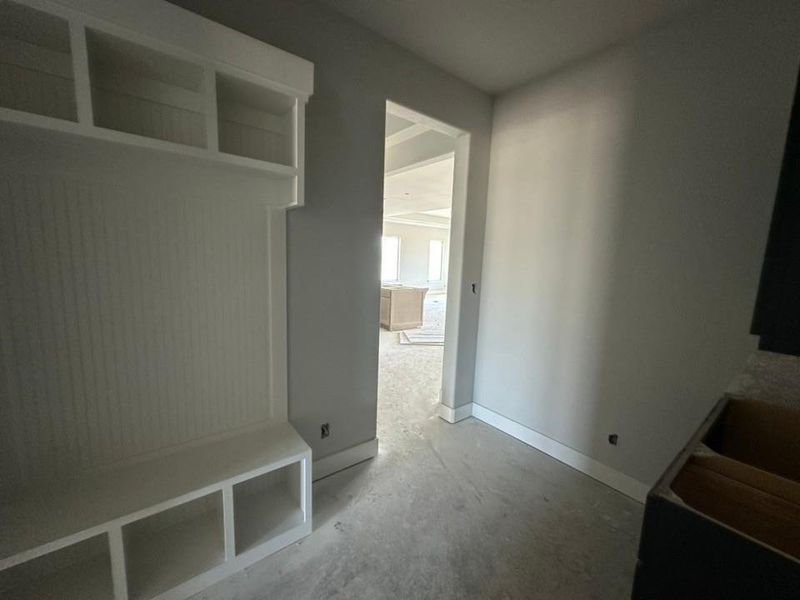 Built-in white storage bench with cubbies and upper shelving, beadboard backing, and painted trim