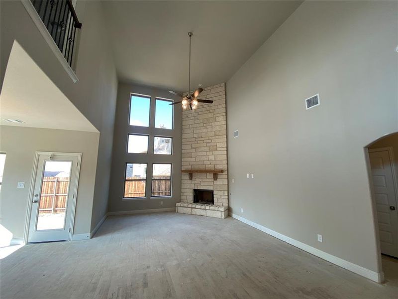 Gorgeous family room has a wall of windows, impressive stone fireplace, ceiling fan, and rich hardwood floors (not stained yet.)