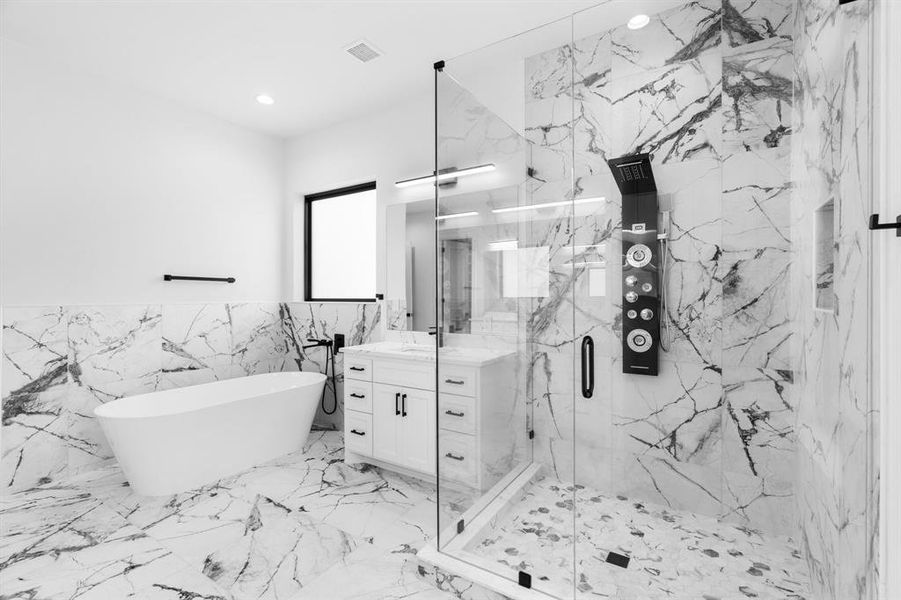 Full bathroom with tile walls, vanity, a marble finish shower, a soaking tub, and marble tiled floors Full bathroom with tile walls, vanity, a marble finish shower, a soaking tub, and marble tiled floors