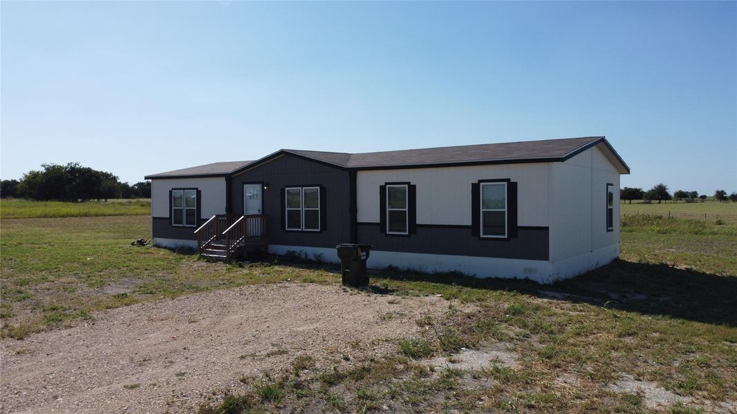 A quaint residence with a contrasting facade of light and dark siding, nestled on a verdant lot. A quaint residence with a contrasting facade of light and dark siding, nestled on a verdant lot.