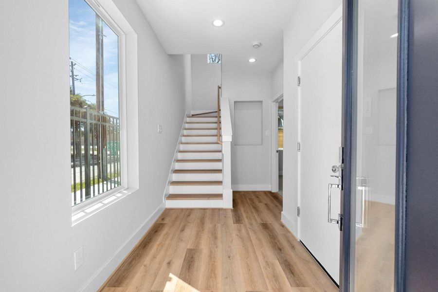 Contemporary staircase with wood treads and clean railing design, complemented by high ceilings and abundant natural light.