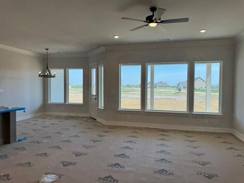 Unfurnished dining area featuring ornamental molding, a ceiling fan, a chandelier, and plenty of natural light