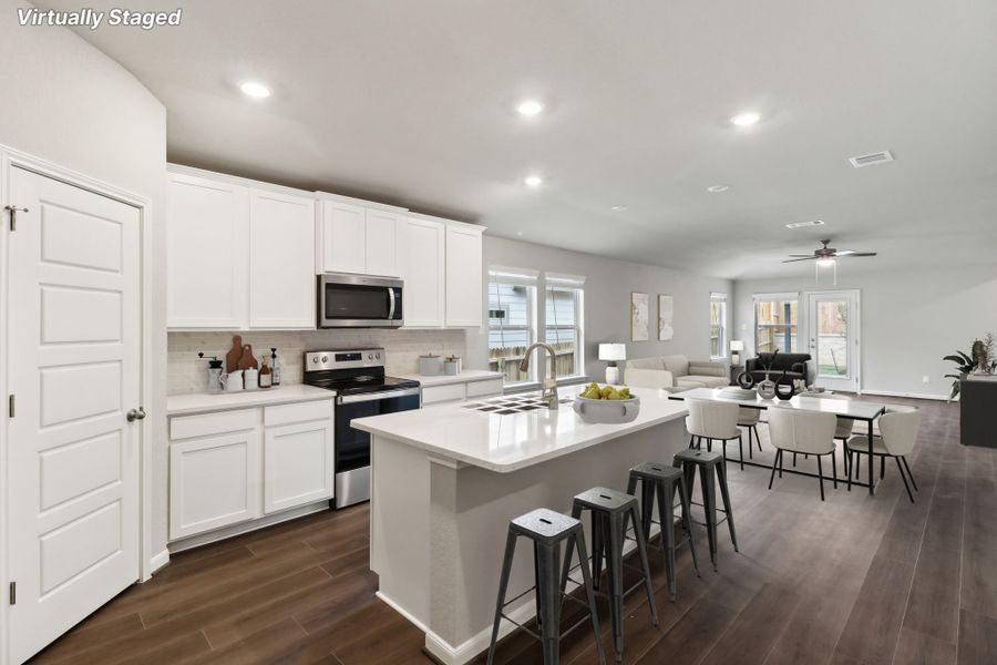 Virtually staged kitchen, dining room, and living room in the Hughes floorplan at a Meritage Homes community.