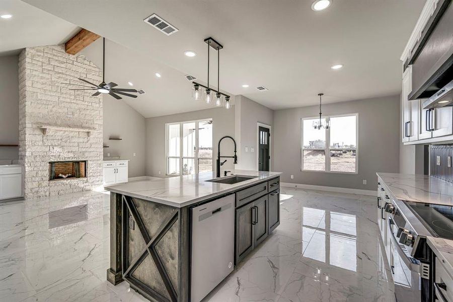 Kitchen featuring visible vents, ceiling fan with notable chandelier, a sink, lofted ceiling with beams, and stainless steel appliances