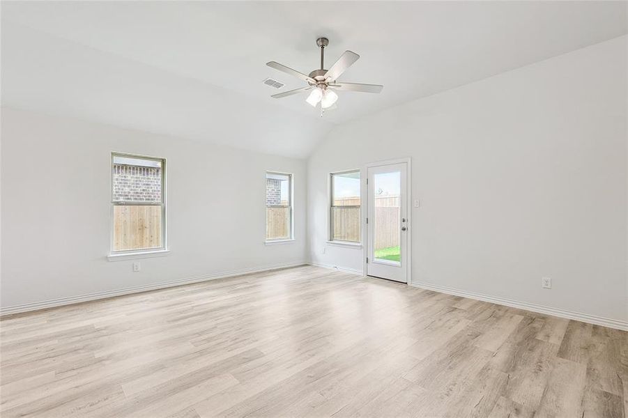 Spare room featuring plenty of natural light, ceiling fan, vaulted ceiling, and light hardwood / wood-style floors