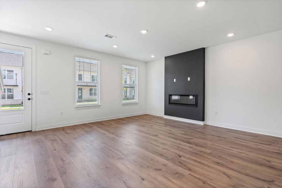 Wood-finish flooring, recessed lighting, modern fireplace, multiple windows, and a glass-paneled door Wood-finish flooring, recessed lighting, modern fireplace, multiple windows, and a glass-paneled door