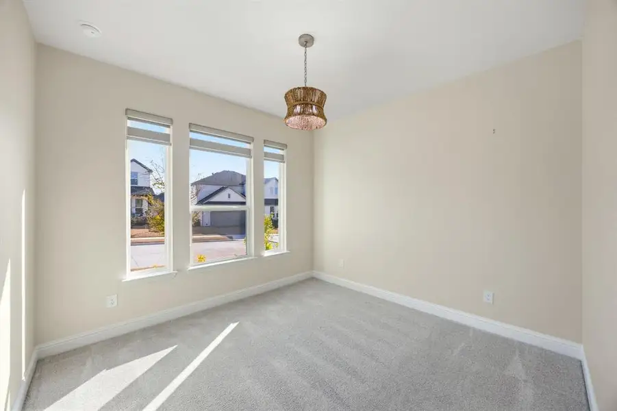 1st level Spare room with light colored carpet and hanging lights