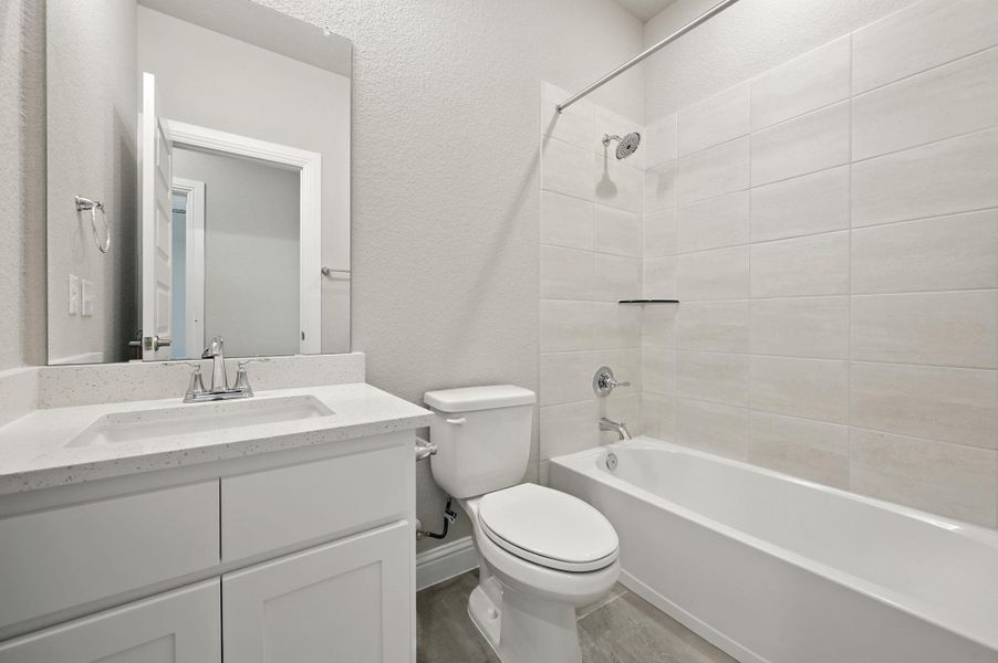 Full bathroom featuring a textured wall, shower / washtub combination, vanity, and wood finished floors