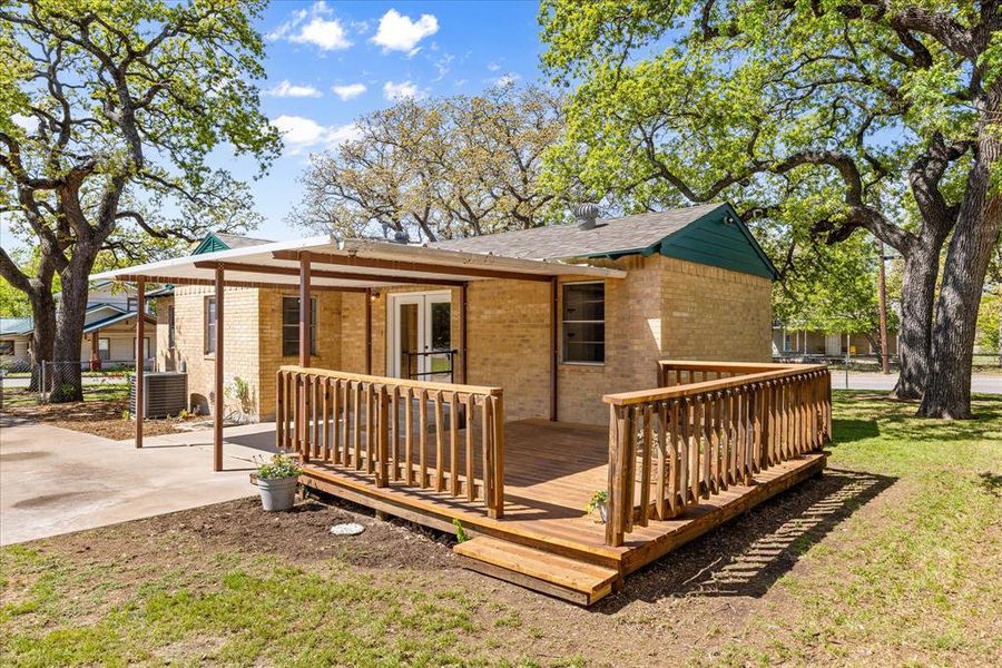 Back of house with cooling unit, a yard, a deck, and brick siding