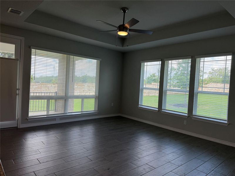 A living area with tray ceilings and expansive windows overlooking the green landscape.