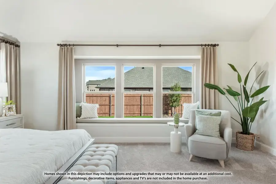 Bedroom with built-in window seat, triple windows, neutral carpet, and sitting area with accent chair