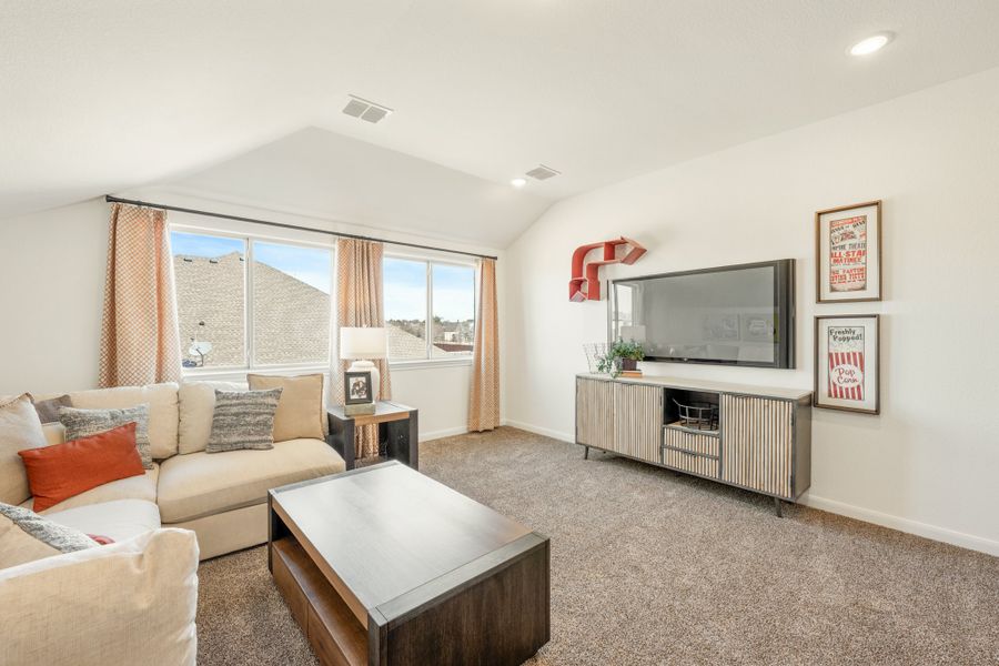 Upstairs living room with vaulted ceiling, sectional sofa, large TV, and carpeted floors