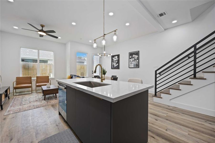 The island is open to the living and dining areas and features sleek light fixtures and quartz countertops. Gorgeous floors adorn the living space.