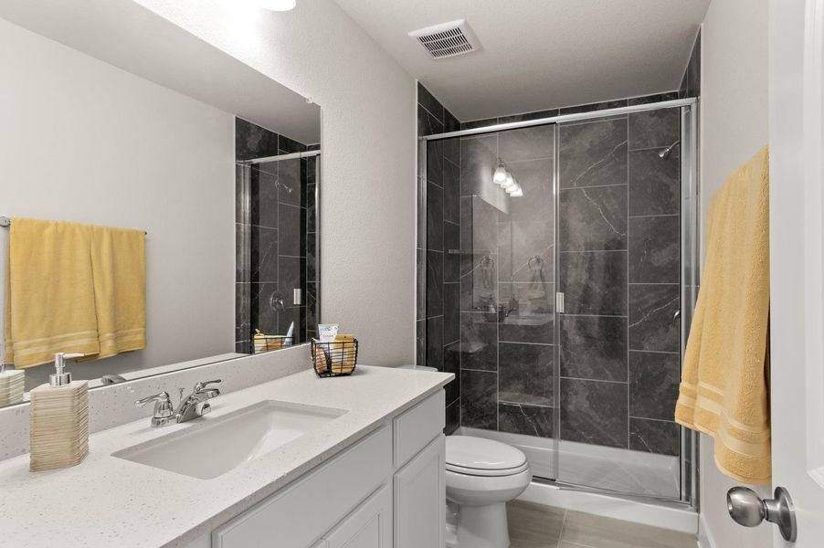 A well-lit primary bathroom with modern fixtures and a glass-enclosed shower creates a refreshing retreat.