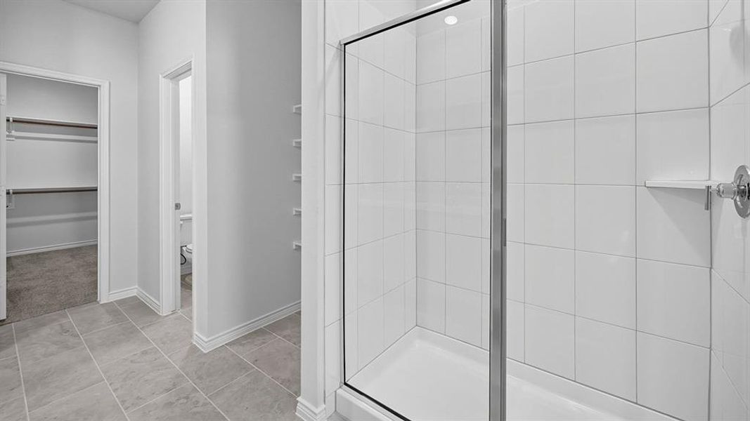 Full bath with a shower stall, a walk in closet, and light tile patterned floors Full bath with a shower stall, a walk in closet, and light tile patterned floors
