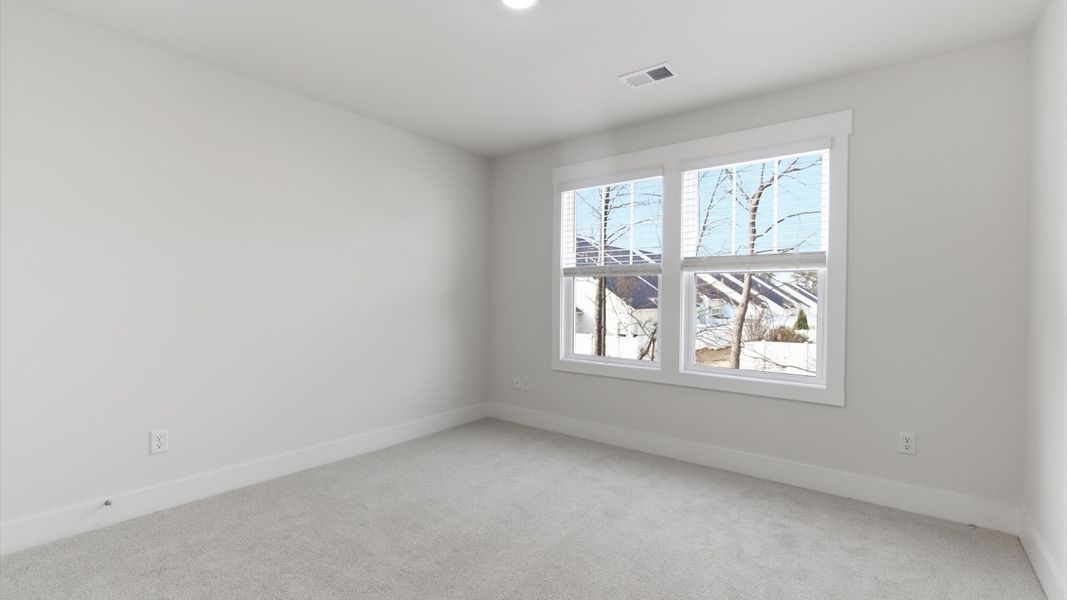 Elegant bedroom retreat featuring soft carpet and oversized windows that create a bright, welcoming space