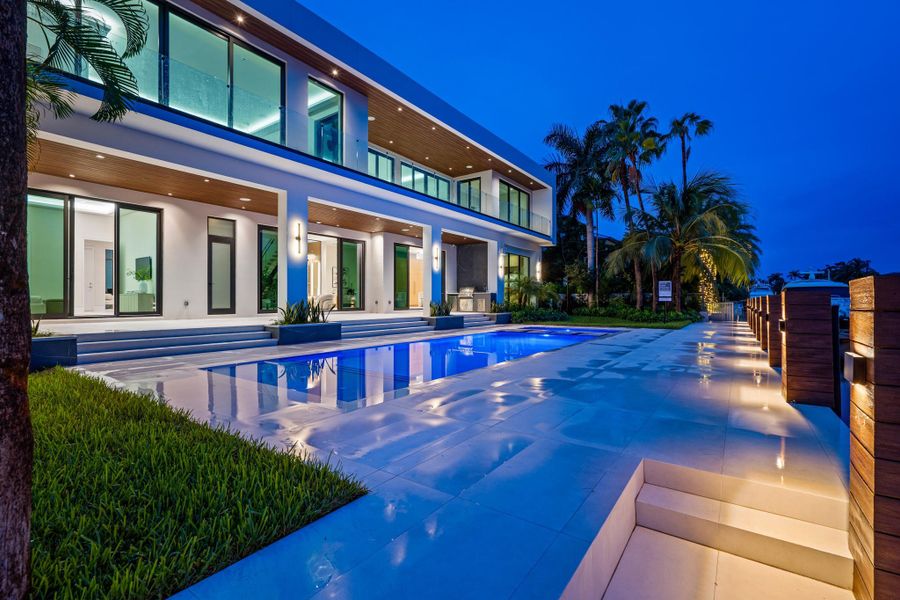Expansive modern residence with sleek glass balconies, covered terraces, and a glowing pool that enhances the waterfront ambiance. Expansive modern residence with sleek glass balconies, covered terraces, and a glowing pool that enhances the waterfront ambiance.