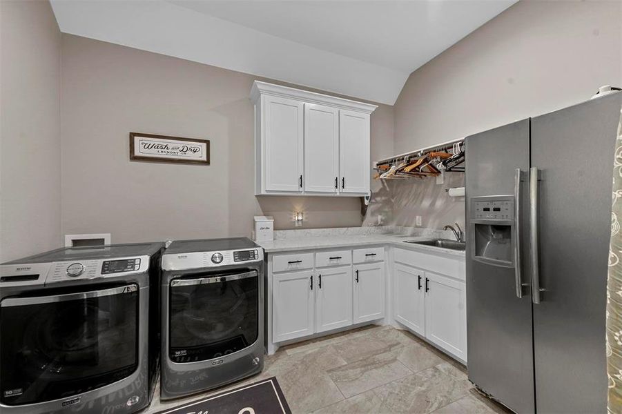 Laundry room with washer and clothes dryer, cabinets, and sink