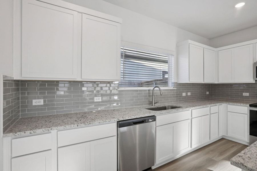 Kitchen featuring appliances with stainless steel finishes, white cabinetry, light stone counters, decorative backsplash, and recessed lighting
