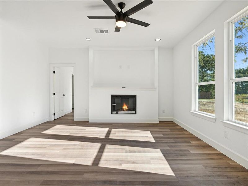 Unfurnished living room featuring ceiling fan, a healthy amount of sunlight, and dark hardwood / wood-style flooring