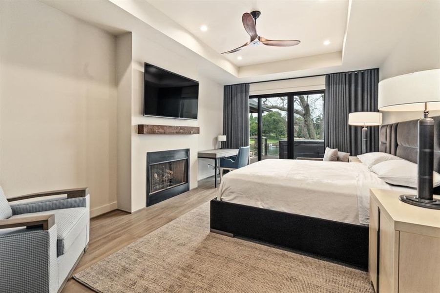 Bedroom with ceiling fan, a raised ceiling, light hardwood / wood-style floors, and access to outside