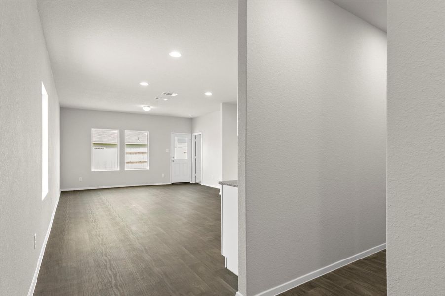 Hallway with dark wood-type flooring, recessed lighting, and a textured wall Hallway with dark wood-type flooring, recessed lighting, and a textured wall