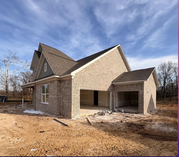 View of home's exterior featuring an attached garage, brick siding, and a shingled roof