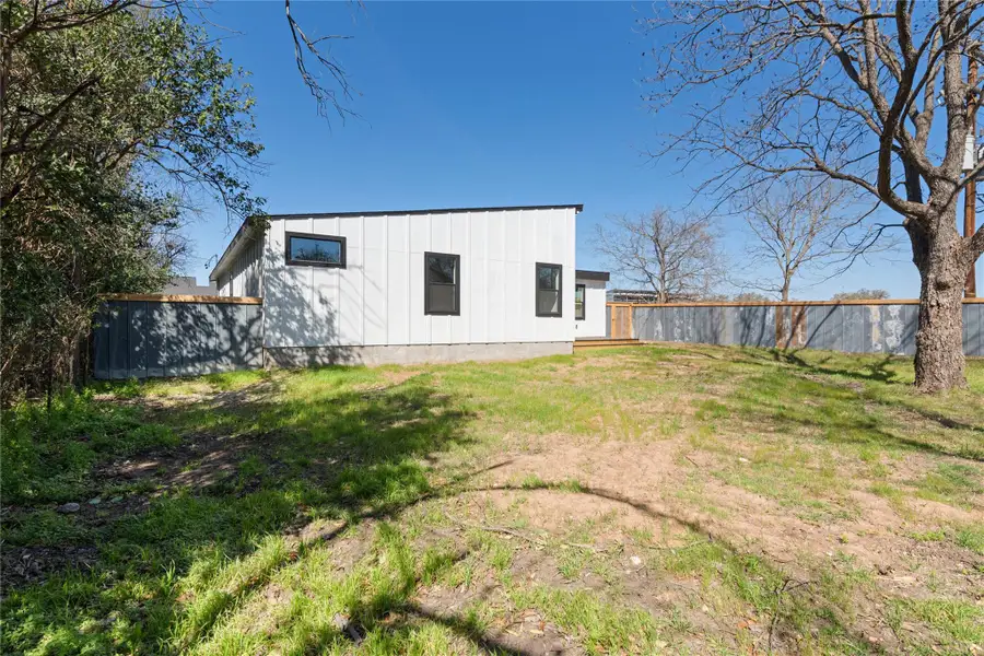 Rear view of house with board and batten siding, a yard, and fence