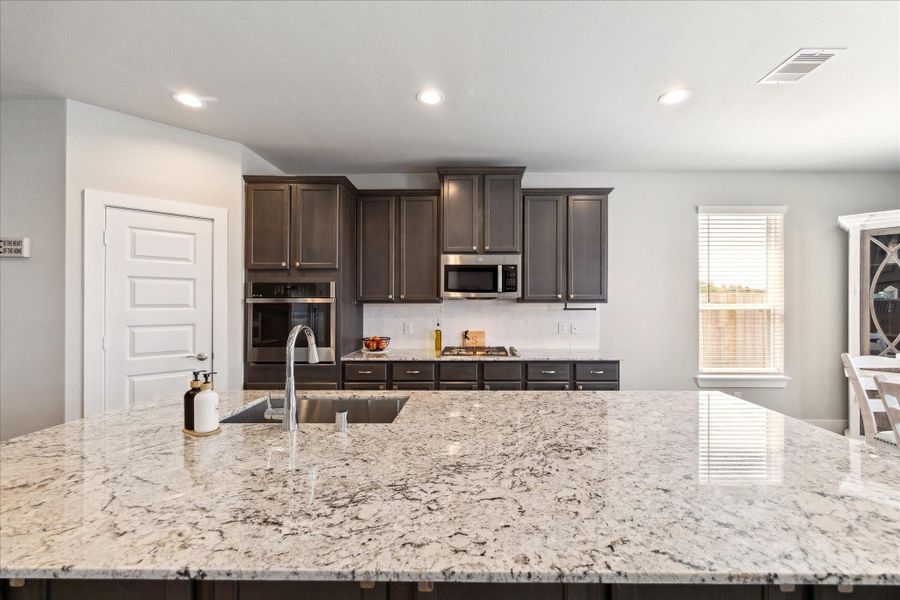 Stylish kitchen with granite countertops, dark cabinetry, and built-in stainless steel appliances. Stylish kitchen with granite countertops, dark cabinetry, and built-in stainless steel appliances.