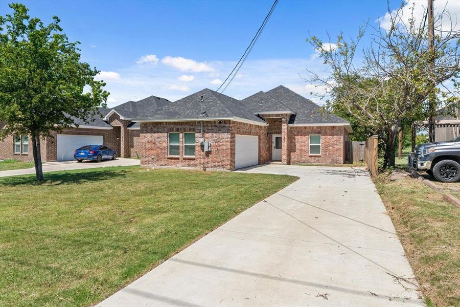 View of front of house featuring driveway, roof with shingles, an attached garage, and brick siding