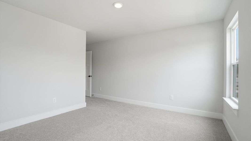 Notable bedroom offering soft carpet, a walk-in closet, and expansive windows overlooking the yard at Creeks at Midway