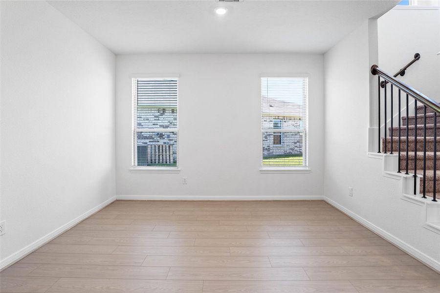 Just beyond the generous entryway, this Flex room awaits. It is highlighted by Bandera vinyl plank flooring in Toasted Sienna, large windows with privacy blinds, custom neutral paint, and recessed lighting. Just beyond the generous entryway, this Flex room awaits. It is highlighted by Bandera vinyl plank flooring in Toasted Sienna, large windows with privacy blinds, custom neutral paint, and recessed lighting.