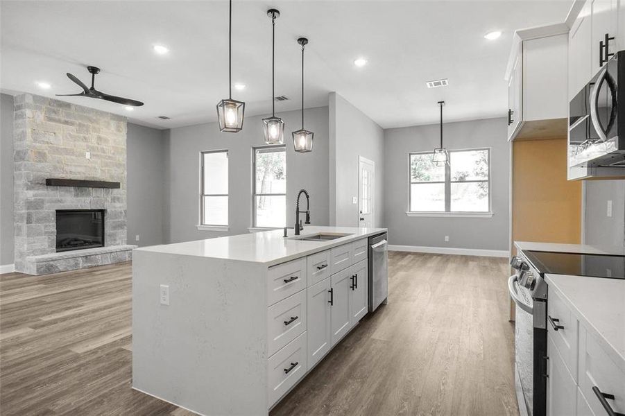 Kitchen featuring stainless steel appliances, ceiling fan, light wood-style flooring, white cabinetry, and recessed lighting Kitchen featuring stainless steel appliances, ceiling fan, light wood-style flooring, white cabinetry, and recessed lighting
